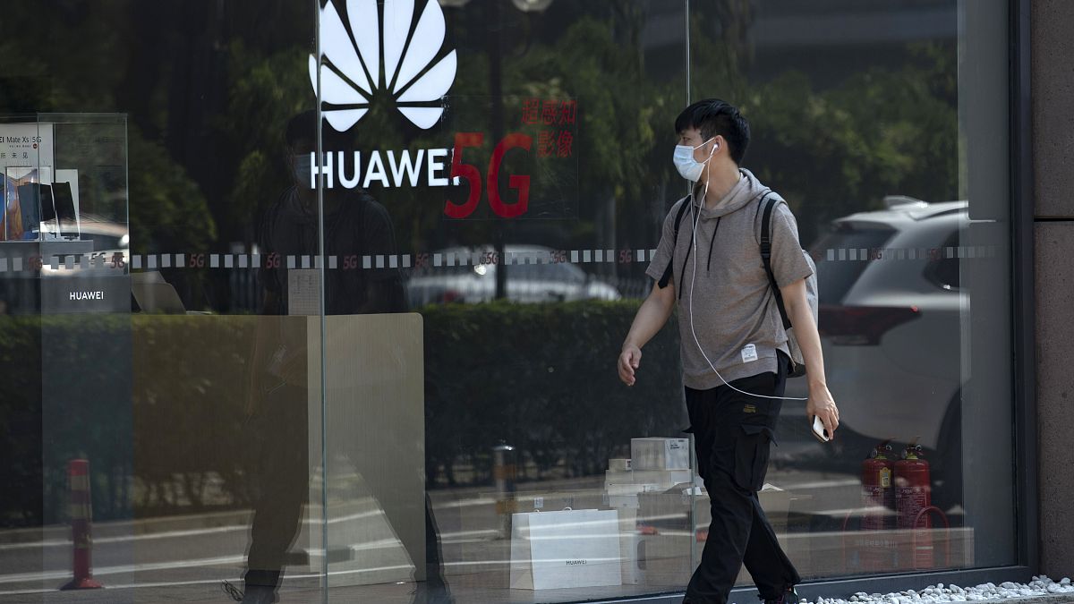 A man wearing a mask to curb the spread of the coronavirus walks past a Huawei store promoting 5G technologies in Beijing on Wednesday, July 15, 2020. 