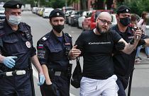 Police officers detain Kommersant newspaper journalist Alexander Chernykh, who is wearing a T-shirt with sign "Freedom to Safronov", during Monday's rally