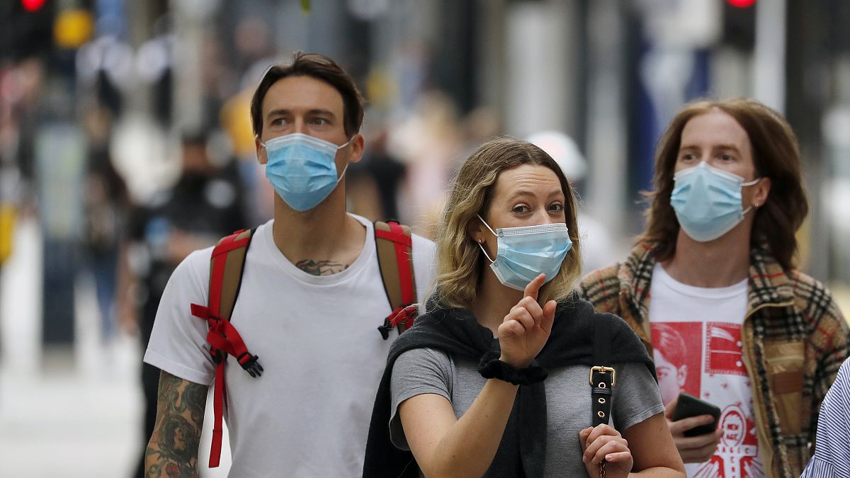 Shoppers wearing protective face masks walk along Oxford Street in London, Tuesday, July 14, 2020.