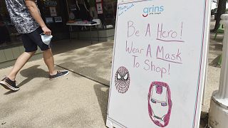 A shopper walks past a sign advising mask usage in downtown St. Joseph, Michigan, US.