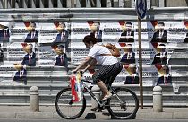 A woman rides a bicycle past electoral campaign posters of the largest opposition party VMRO-DPMNE