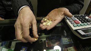 An Iranian goldsmith counts his gold coins at a gold market in the main old Bazaar of Tehran, Iran