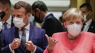 German Chancellor Angela Merkel, right, and French President Emmanuel Macron arrive for a round table meeting at an EU summit in Brussels, Friday, July 17, 2020