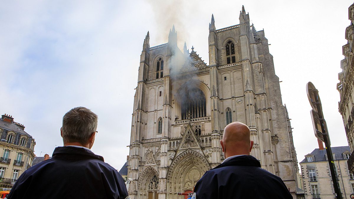 French police officers look at the Gothic St. Peter and St. Paul Cathedral, in Nantes, damaged by a blaze on Saturday morning. July 18, 2020