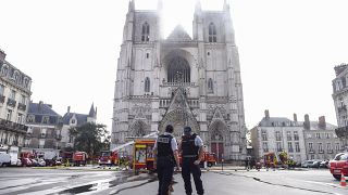French Police officers stand ready as firefighters are at work to put out a fire at the Saint-Pierre-et-Saint-Paul cathedral in Nantes.