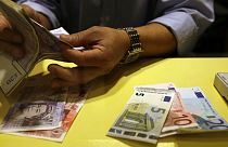 An employee counts British pounds and Euro notes at a currency exchange office