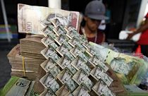 Venezuelan Bolivars are weaved together at a vendor's table selling art and bags made from the currency