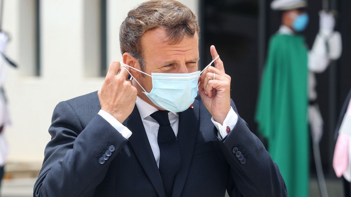 French President Emmanuel Macron puts on a face mask after arriving at Mauritania's Nouakchott--Oumtounsy International Airport on June 30, 2020