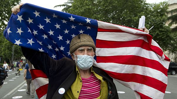 An elderly activist, wearing a face mask to protect against coronavirus, waves the US flag during a rally in Tbilisi, Georgia An elderly activist, wearing a face mask to protect against coronavirus, waves the US flag during a rally in Tbilisi, Georgia