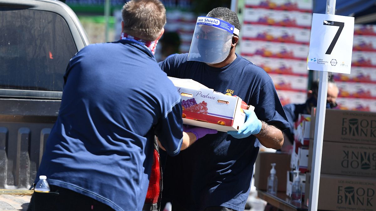 متطوعون يحمّلون مواد البقالة المجانية في السيارات للمحتاجين في أحد بنوك الطعام في حي كرينشو في لوس أنجلوس خلال جائحة فيروس كورونا
