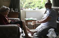 A district nurse changes the dressings on the legs of 86-year-old Margaret Ashton during a home visit.