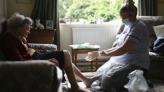 A district nurse changes the dressings on the legs of 86-year-old Margaret Ashton during a home visit.