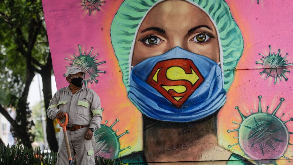 Un jardinero trabaja junto a un mural del artista urbano Applez, en Ciudad de México