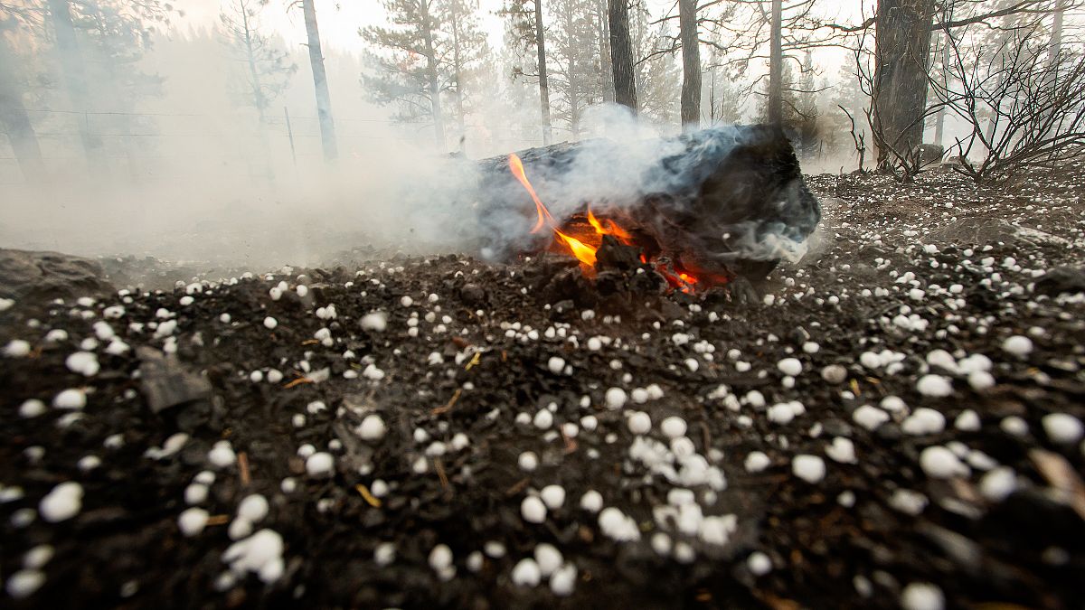 A log keeps burning as hail lies on the ground near Susanville, California. July 21, 2020 