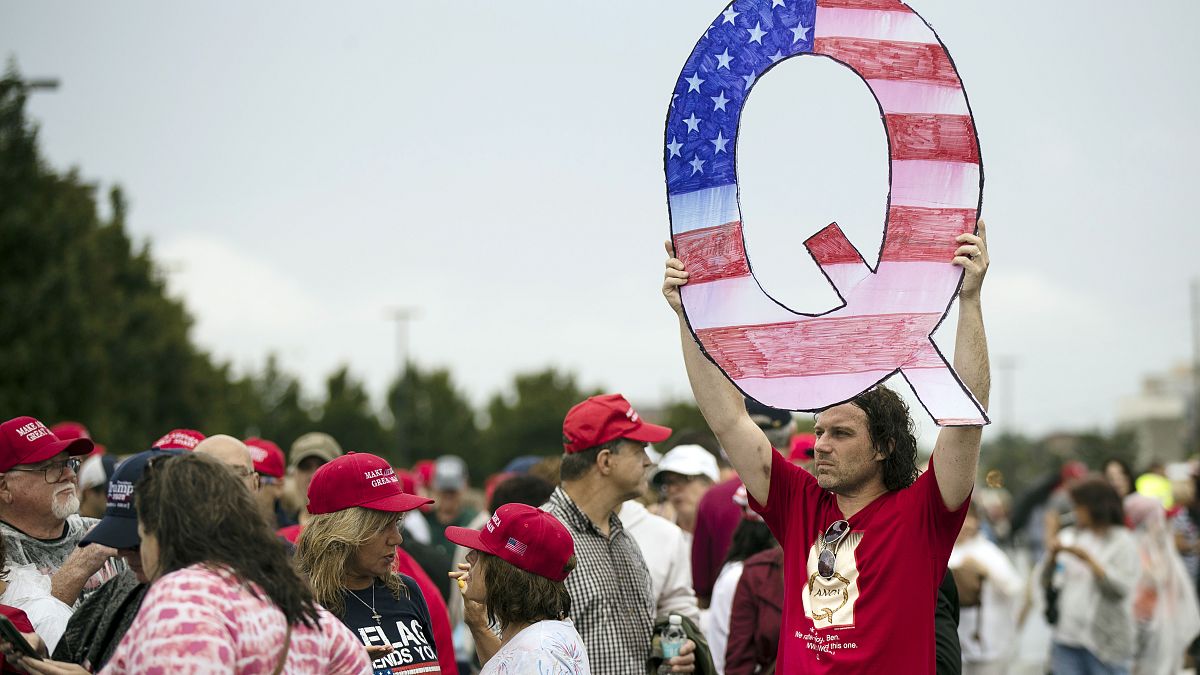 David Reinert holding a Q sign waits in line with others to enter a campaign rally with President Donald Trump and U.S. Senate candidate Rep. Lou Barletta, August 2018