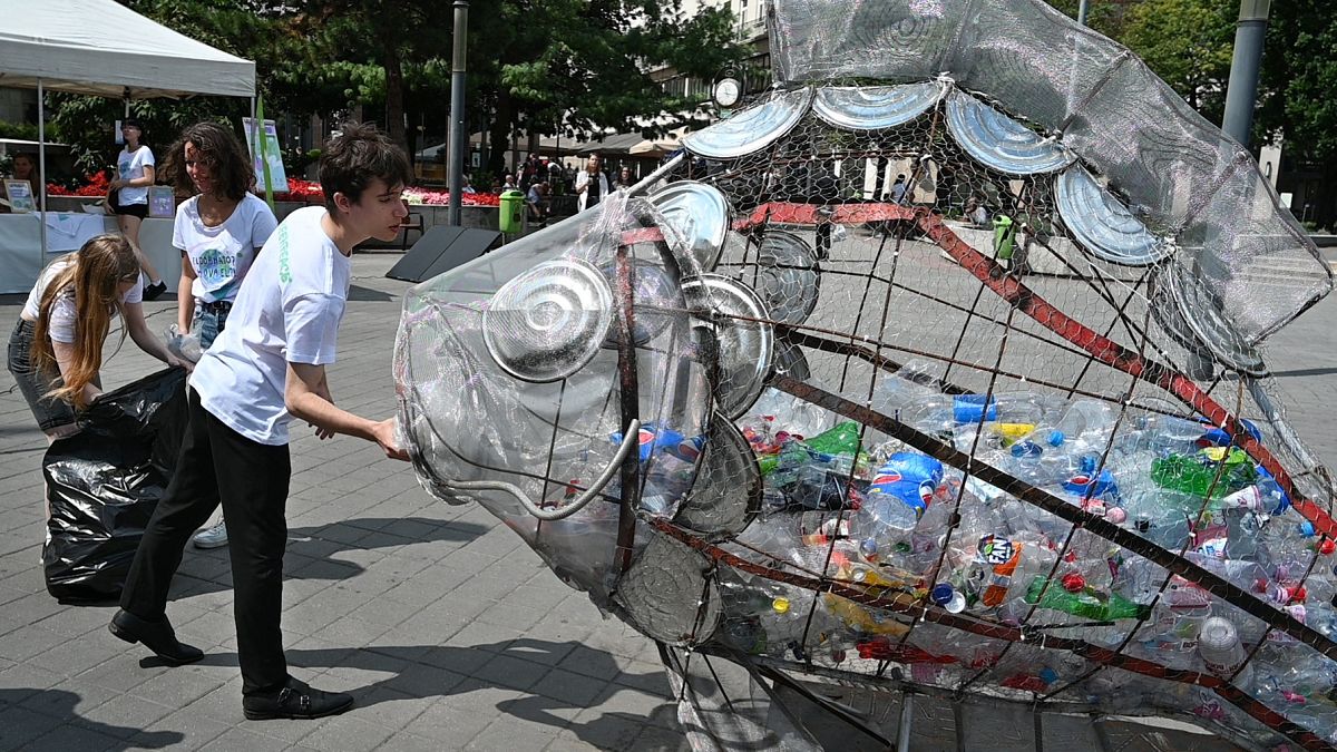 Des enfants mettent des bouteilles en plastique dan un collecteur en forme de poisson dans le centre de Budapest, le 20 juillet 2020