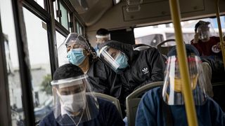 Commuters, wearing protective face masks and face shields, travel on a public bus in Lima, Peru, Wednesday, July 22, 2020.