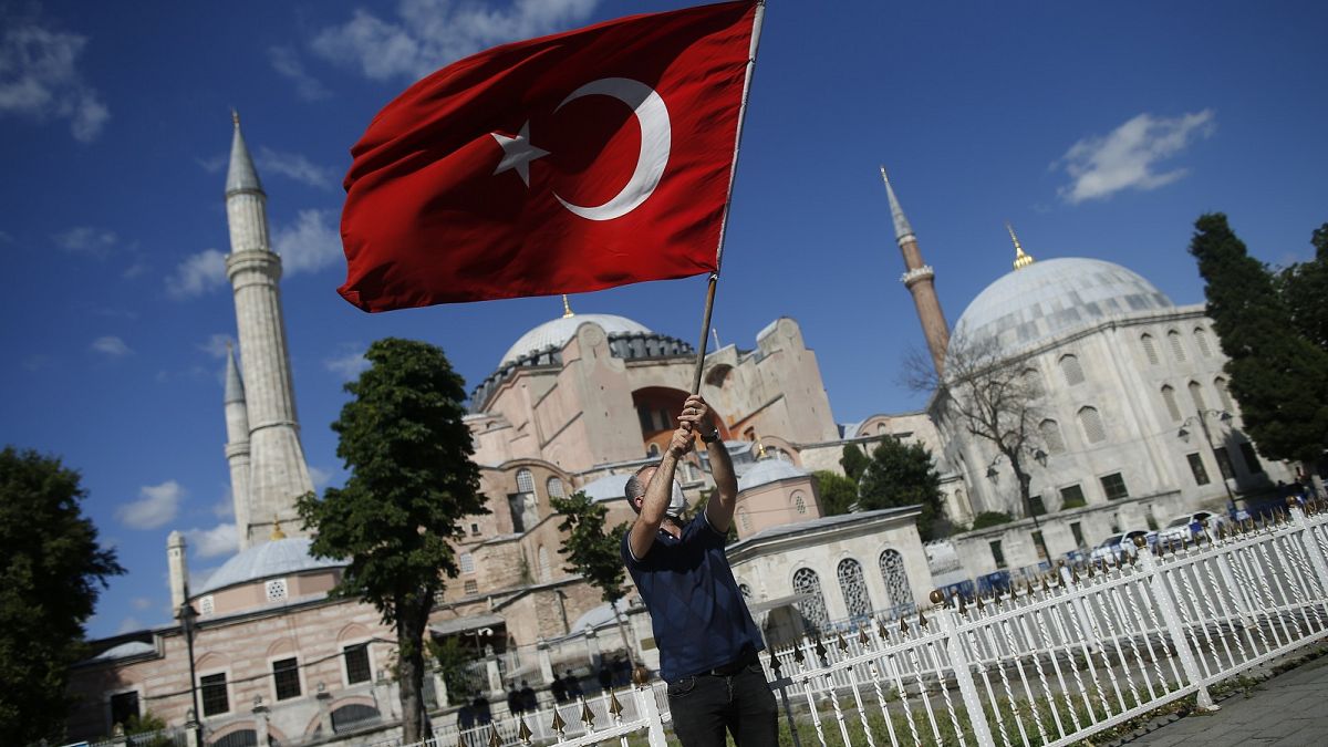 A man waves a Turkish flag outside the Hagia Sophia, following Turkey's decision to convert it into a mosque