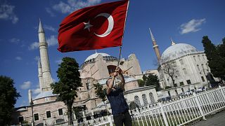 A man waves a Turkish flag outside the Hagia Sophia, following Turkey's decision to convert it into a mosque