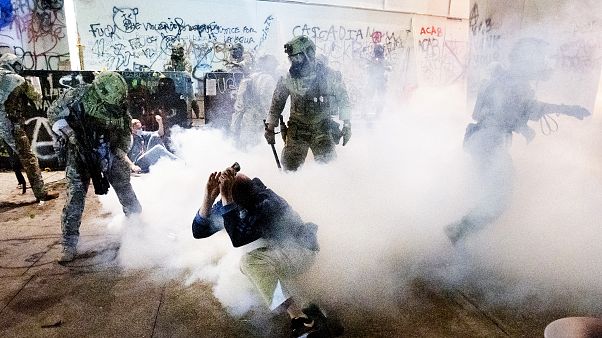 Agentes federales usan irritantes químicos y municiones de control de multitudes para dispersar una manifestación antirracista junto al Palacio de Justicia de Portland. Agentes federales usan irritantes químicos y municiones de control de multitudes para dispersar una manifestación antirracista junto al Palacio de Justicia de Portland.