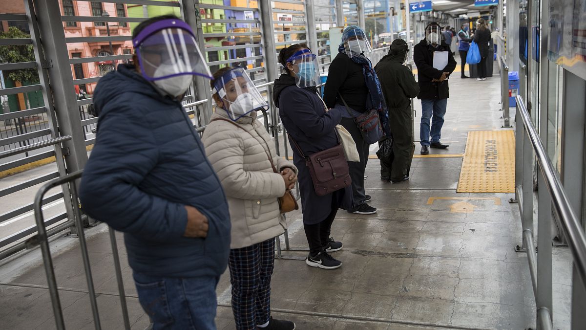 Peruanos esperan la llegada de un autobús en una parada de Lima