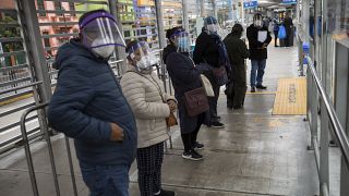 Peruanos esperan la llegada de un autobús en una parada de Lima