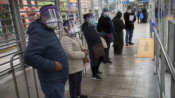 Peruanos esperan la llegada de un autobús en una parada de Lima Peruanos esperan la llegada de un autobús en una parada de Lima