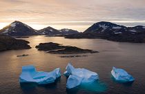 In this Aug. 16, 2019, photo, large Icebergs float away as the sun rises near Kulusuk, Greenland. 