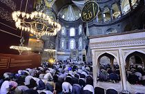 People pray inside the Byzantine-era Hagia Sophia, with sail-like drapes, top, covering Christian mosaics,
