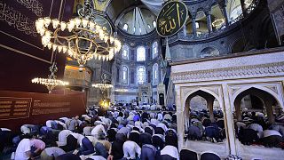 People pray inside the Byzantine-era Hagia Sophia, with sail-like drapes, top, covering Christian mosaics,