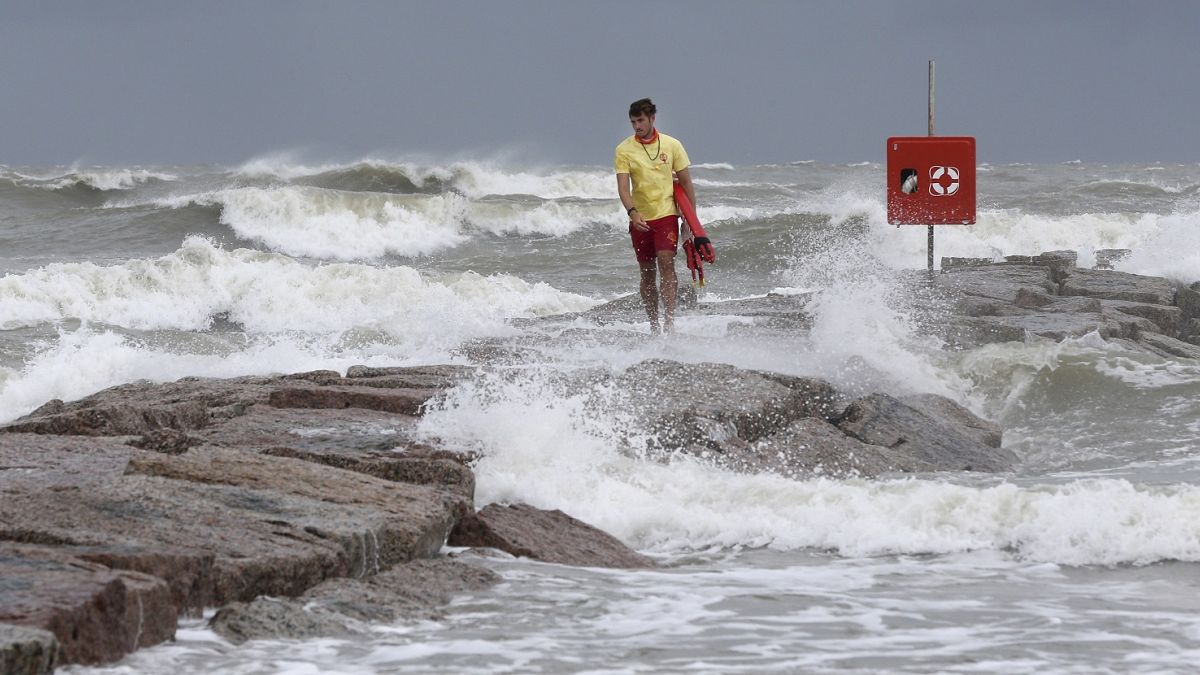 Galveston Island Beach Patrol lifeguard Matthew Herdrich walks along rocks as waves kicked up by Tropical Storm Hanna wash over them.
