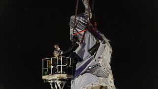 City crews inspect the straps that are around the Christopher Columbus statue in Chicago's Grant Park as they begin to remove it.