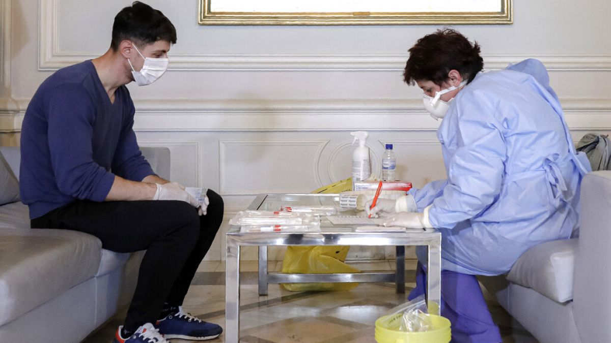 A health official takes samples for a coronavirus test from a journalist in Bucharest, Romania, March 13, 2020.