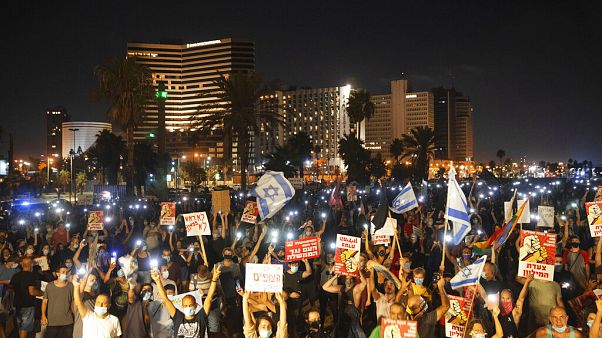 Protesters hold signs during a protest against Israel's Prime Minister Benjamin Netanyahu in Tel Aviv, Israel, on July 25, 2020 Protesters hold signs during a protest against Israel's Prime Minister Benjamin Netanyahu in Tel Aviv, Israel, on July 25, 2020