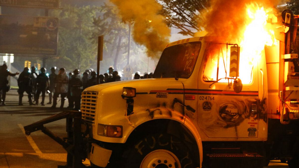 Police stand in front of a utility vehicle that was set on fire by protesters during a demonstration in Richmond, Virginia, July 25, 2020