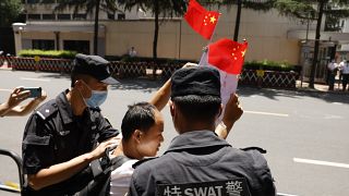 Policías detienen a un ciudadano que entonaba cánticos nacionalistas mientras agitaba banderas chinas frente al edificio del consulado de EEUU en Chengdu