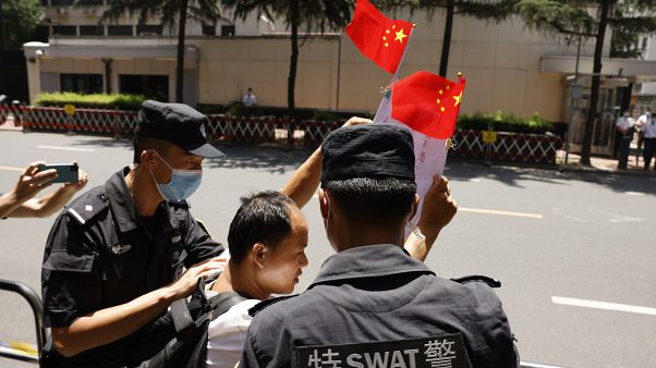 Policías detienen a un ciudadano que entonaba cánticos nacionalistas mientras agitaba banderas chinas frente al edificio del consulado de EEUU en Chengdu Policías detienen a un ciudadano que entonaba cánticos nacionalistas mientras agitaba banderas chinas frente al edificio del consulado de EEUU en Chengdu