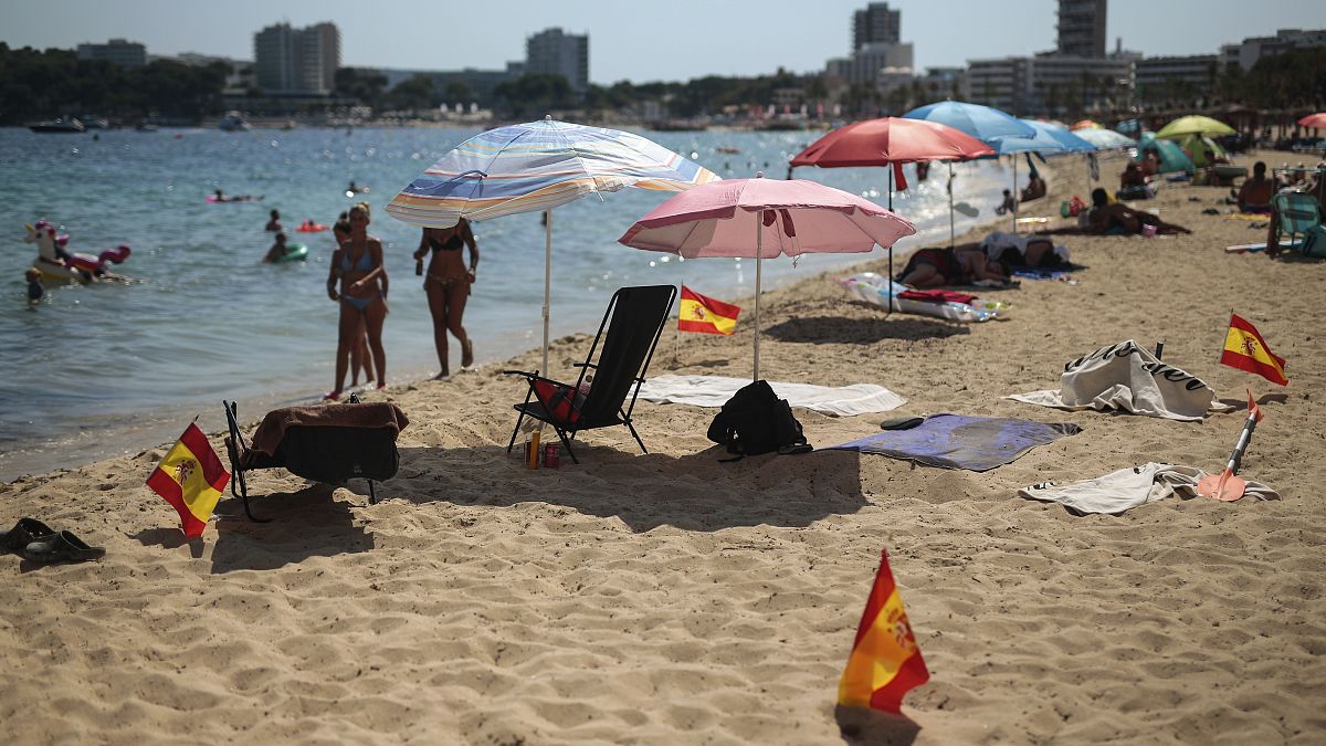 Las banderas españolas se usan como señal de distanciamiento social en la arena en Palma de Mallorca, España, el domingo 26 de julio de 2020. 