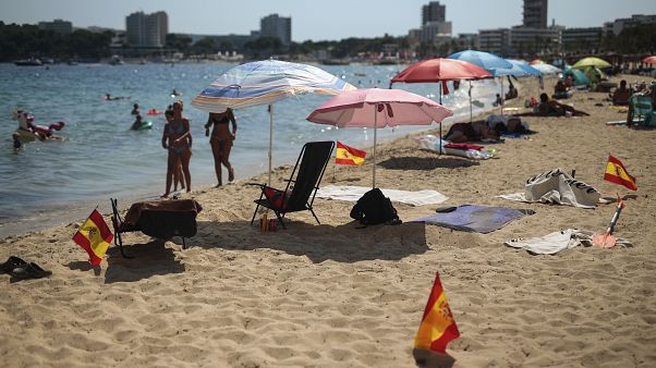 Las banderas españolas se usan como señal de distanciamiento social en la arena en Palma de Mallorca, España, el domingo 26 de julio de 2020. Las banderas españolas se usan como señal de distanciamiento social en la arena en Palma de Mallorca, España, el domingo 26 de julio de 2020.