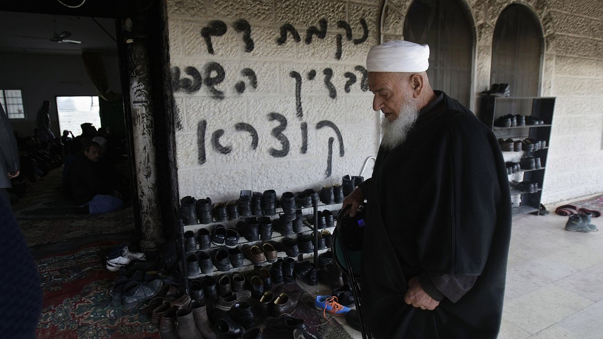 من الأرشيف: رجل فلسطيني يزور مسجدًا متضررًا في قرية دير استيا بالضفة الغربية حيث اشتعلت النيران في باب المسجد 
