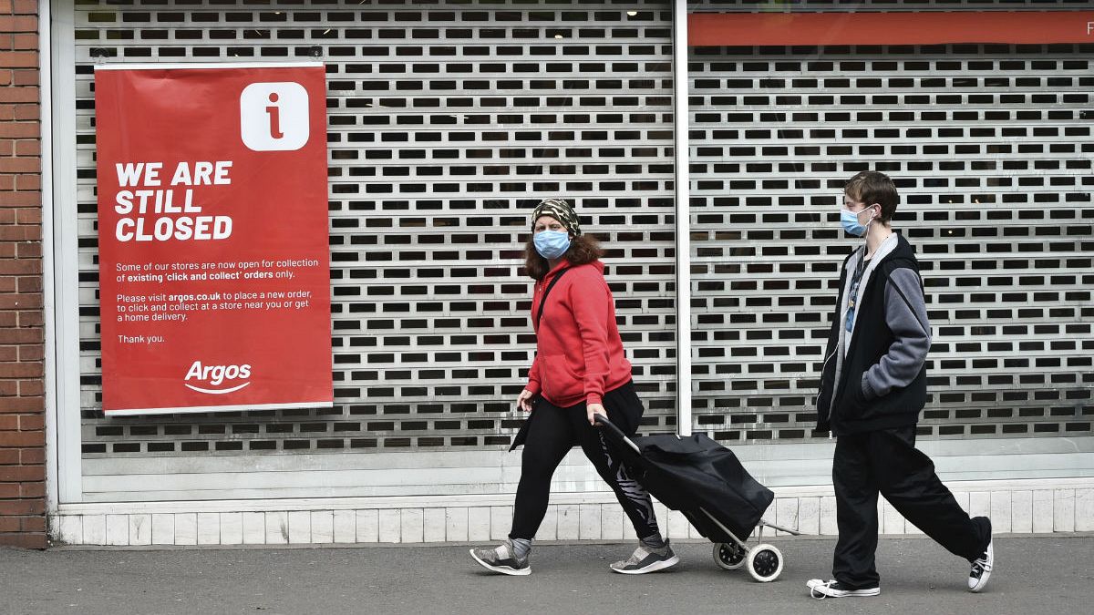 Members of the public walk past a closed shop in Leicester city centre, England