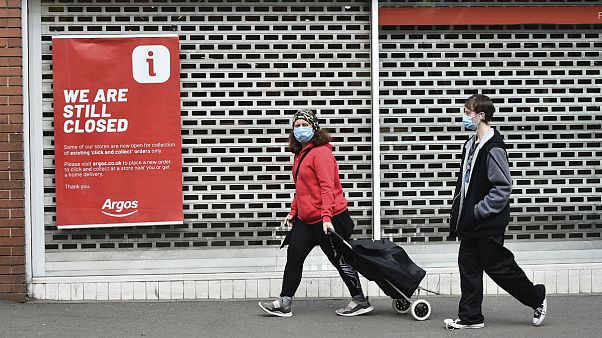 Members of the public walk past a closed shop in Leicester city centre, England Members of the public walk past a closed shop in Leicester city centre, England