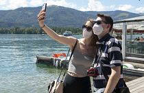 A couple make selfies at the lake side in St. Wolfgang, Austria