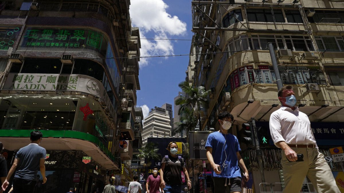 People wearing face masks to help curb the spread of the coronavirus walk on a downtown street in Hong Kong