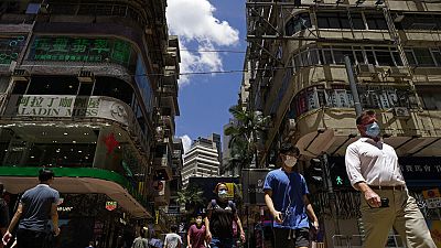 People wearing face masks to help curb the spread of the coronavirus walk on a downtown street in Hong Kong
