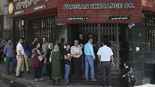 People line up in front of a currency exchange shop to buy U.S. dollars and euros, in downtown Tehran, Iran