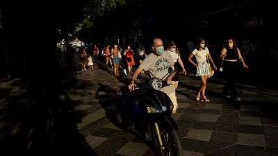 Personas con mascarillas para prevenir la propagación del coronavirus, caminan por una calle de Madrid, España, el  28 de julio de 2020. 