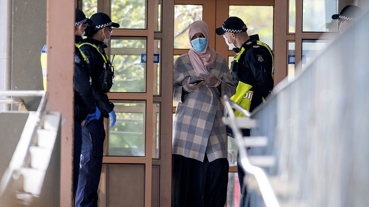 Police talk to a woman at housing commission apartments under lockdown in Melbourne, Australia, on Monday, July 6, 2020. 