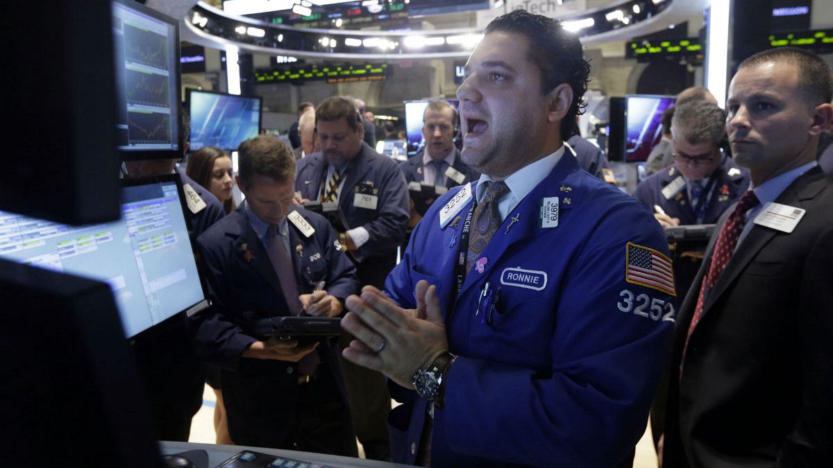 Specialist Ronnie Howard, center, calls out prices as he works at his post on the floor of the New York Stock Exchange