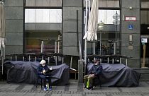 An elderly couple sit outside a closed bar in Munich, Germany